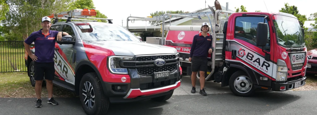 Bar Plumbing team standing beside two Bar Plumbing trucks